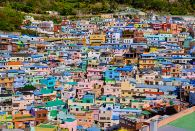 An aerial view of Gamcheon Culture Village in Busan, South Korea, with densely packed colourful houses in pastel shades of pink, blue, yellow and green cascading down a hillside