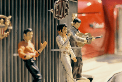 Vintage Elvis figurines zip tied to the grill of a classic red car
