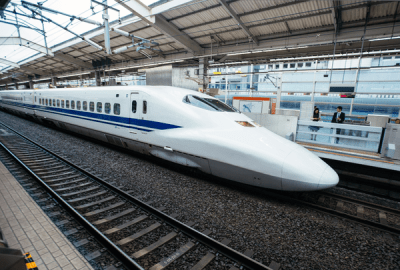 A white and blue Shinkansen bullet train stopped at a Japanese railway station platform