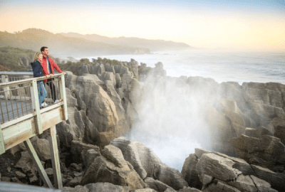 A couple watch sea spray from a blowhole, Pancake Rocks, Punakaiki, NZ