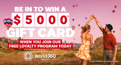 Couple dancing beneath hot air balloons over a scenic valley featuring a chance to win a $5000 gift card when you join our free loyalty program