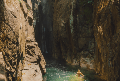 Silky waterfall cascading into a serene rock pool surrounded by lush tropical rainforest at Babinda Boulders near Cairns in Queensland