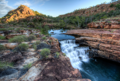 A waterfall rushes down the red stratified rock of Bell Gorge in the Kimberley region