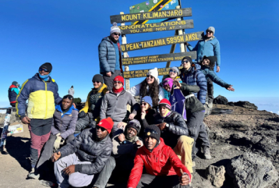 A group of hikers pose for a photo atop the rocky summit of Mount Kilimanjaro