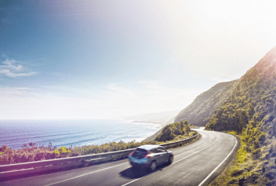 Cars drive along the Great Ocean Road on a sunny afternoon