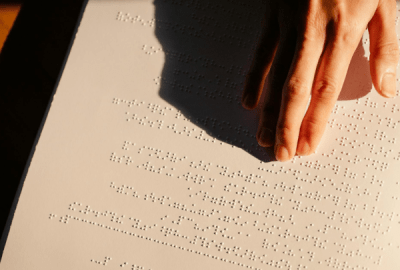 A hand reads a Braille menu