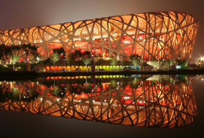 Beijing's 'birds nest" national stadium lit up at night and reflected in a nearby lake 