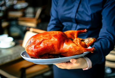 A freshly cooked Peking Duck in the arms of a waiter