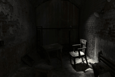 An eerie lamp lights up a derelict chair in a condemned room