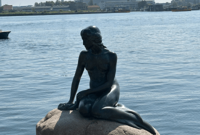 A bronze statue of Hans Christian Andersen's Little Mermaid sits on a rock by the sea at Copenhagen