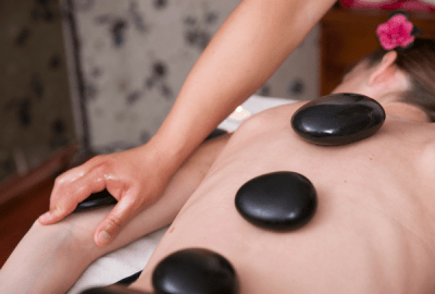 A woman lies face down with massage stones placed on her back