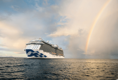 A cruise ship sails beside a rainbow