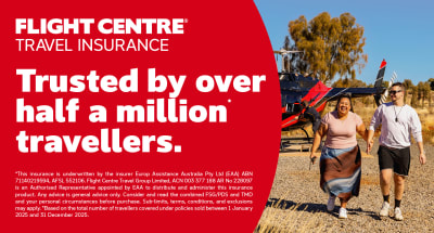 Travellers walking hand in hand beside a helicopter promoting Flight Centre Travel Insurance trusted by over half a million travellers