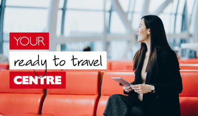 Your ready to travel centre - Asian businesswoman on a red chair waiting at an airport holding a tablet