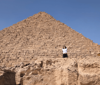 Sara Winfield stands and waves from below one of the Great Pyramids of Giza
