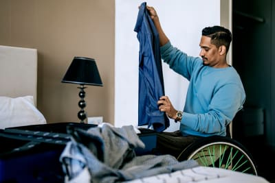 A wheelchair user packing a suitcase