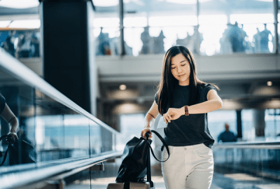 A businesswoman checks her watch while standing on an airport escalator 