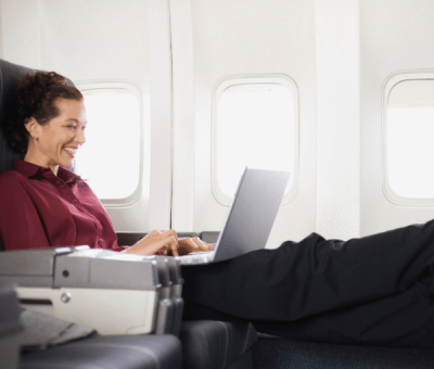 A business woman working on a laptop puts her feet up in business class