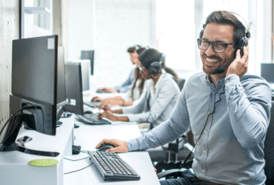 A man smiles as he chats into a headset
