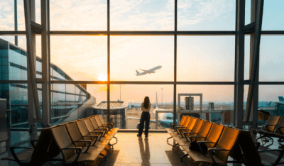 lady standing at airport watching plane takeoff
