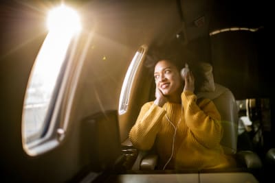 Mixed heritage woman wearing headphones on airplane