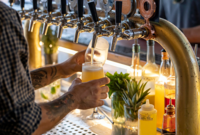 A barman pours beer from a tap at a rooftop bar
