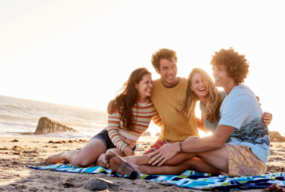 Four happy friends sitting on the beach
