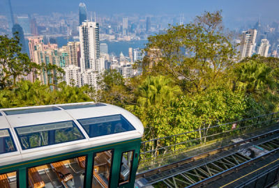 A cable car hovers among trees above the Hong Kong skyline