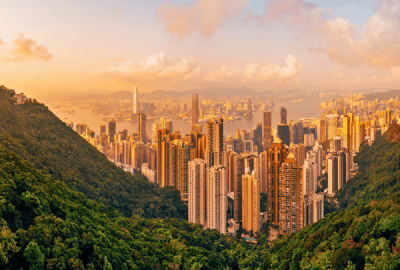 The Hong Kong cityscape viewed down a steep, tree-covered valley