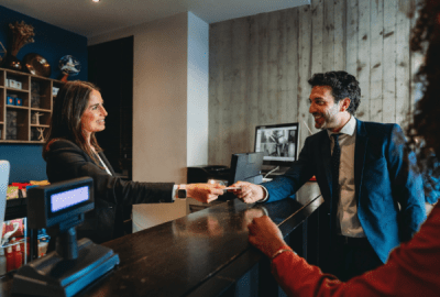 Hotel reception handing over the room key to a couple of guests