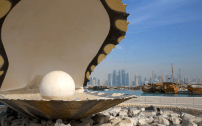 Giant pearl and clam statue with skyscrapers and boats in the background
