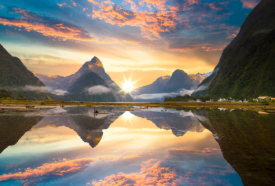 Mitre Peak and other steep mountains reflected in the still waters of Milford Sound at sunset