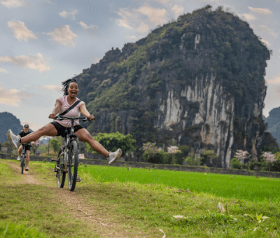 Woman laughs while doing a trick on a bicycle in a field