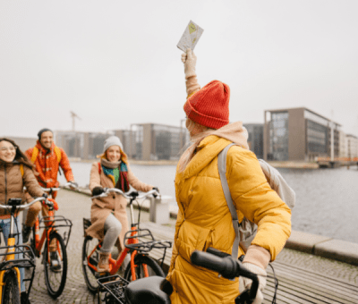A group of young people laugh while riding bikes down a wharf
