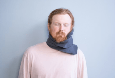 A man wears a wrap-around neck pillow