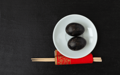 Japan Hakone black eggs served on a white plate with chopsticks beside them.