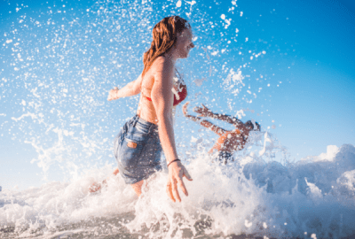 A couple splashing and jumping into the surf.