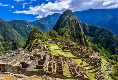 The sun shines on the mountainous stony ruins of Machu Picchu