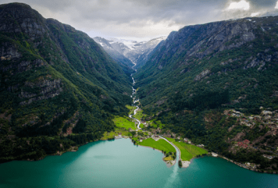 Aerial view of a river winding down a valley from mountains into a Norwegian Fjord