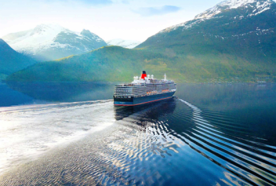 A cruise ship sails on calm waters with a mountainous background