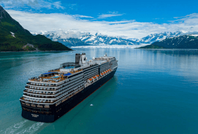 A cruise ship sails along a channel where mountains and glaciers meet the sea