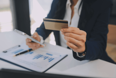 A woman works out finances holding a credit card and an iphone