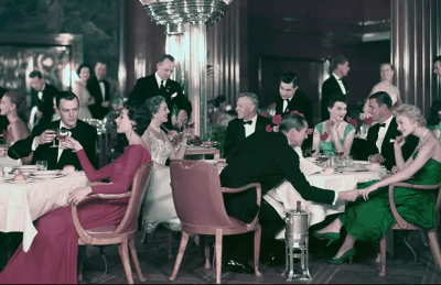 Well dressed people circa 1940s gather for dinner in a cruise ship's grand dining room