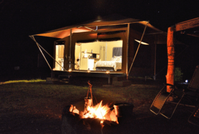 A bonfire in front of a glamping tent at night