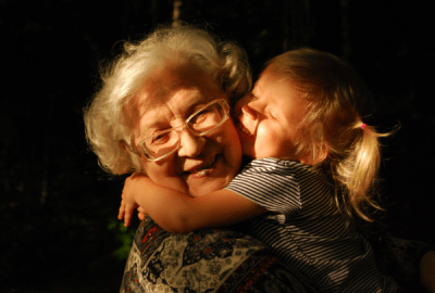 A young girl cuddles an old woman