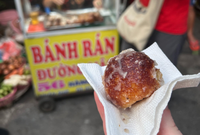 A banh ran hot off the street cart is served up in a paper napkin