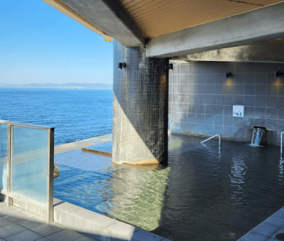 An open-air Japanese onsen hot spring pool overlooking the sea