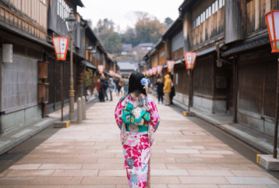 A woman in traditional Japanese costume walks down a quiet backstreet.