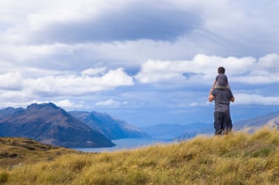 Boy sits on shoulders of father admiring views above Queenstown, New Zealand
