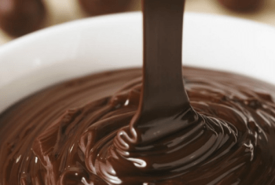 Molten chocolate is poured swirling into a white bowl